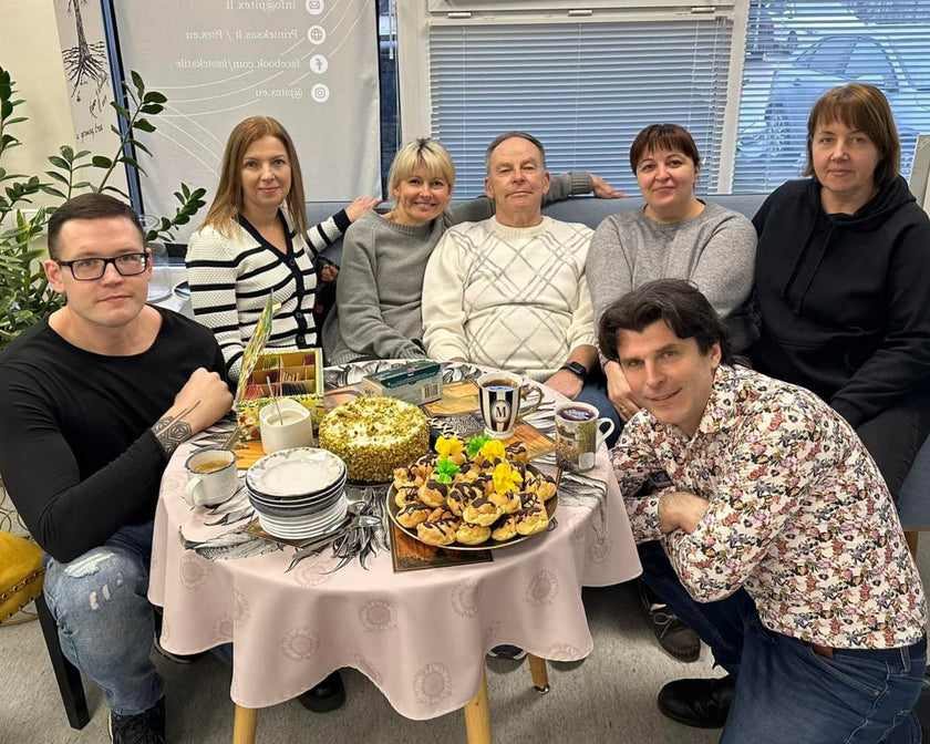 Group of people sitting around a table with food in an office setting